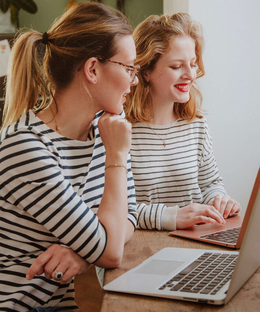 Deux femmes souriant devant un ordinateur